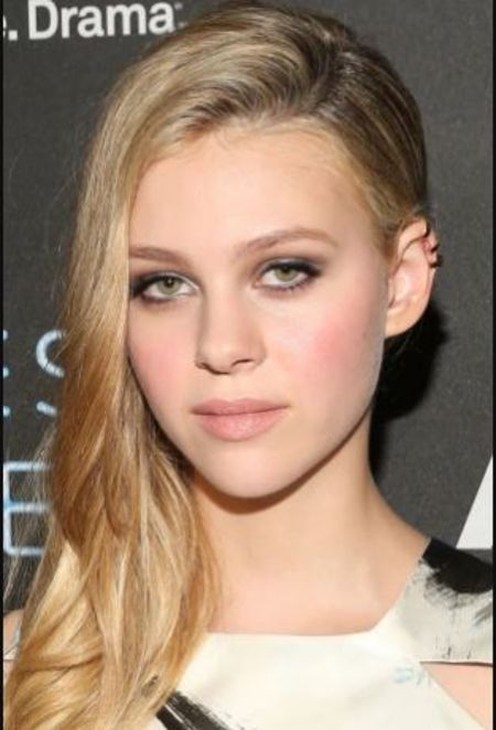 Nicola Peltz in a white t-shirt poses for a picture.